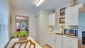 A modern kitchen with white cabinets, a microwave, and a dining area with a table and chairs. - Idyllic Cave Spring Studio w/ Patio & Fire Pit! (Roanoke)