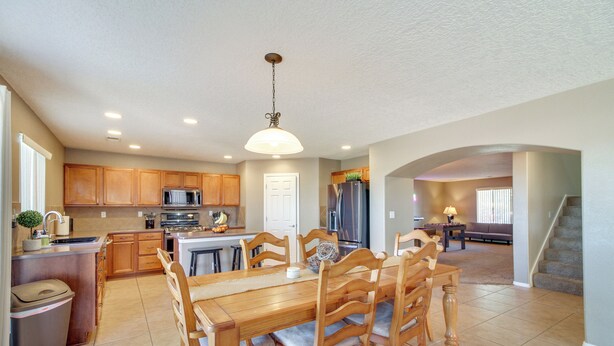 A spacious kitchen with wooden cabinets, a central island, and a dining area with a large wooden table and chairs. - Chic New Mexico Retreat w/ Patio, Grill & Fire Pit (Los Lunas)
