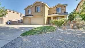 A two-story house with a garage, a well-maintained lawn, and a gravel driveway. - Chic New Mexico Retreat w/ Patio, Grill & Fire Pit (Los Lunas)