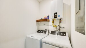 Ein Waschraum mit zwei weißen, frontbeladenen Waschmaschinen und einem an der Wand montierten Warmwasserbereiter.