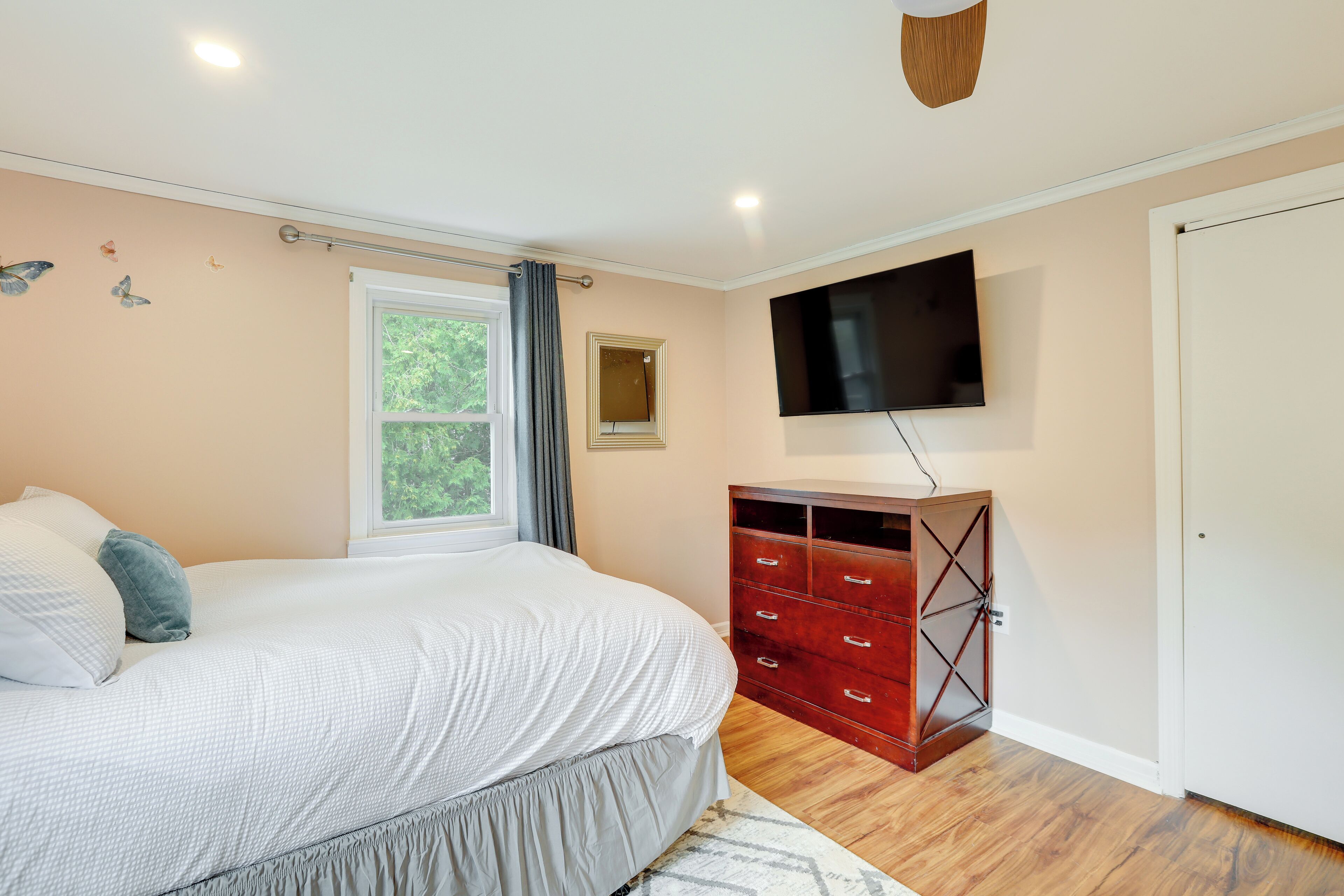 Een slaapkamer met een bed, een kaptafel, een televisie en een raam.