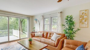 En rummelig stue med en lædersofa, et træbord og et stort vindue med udsigt til en balkon.