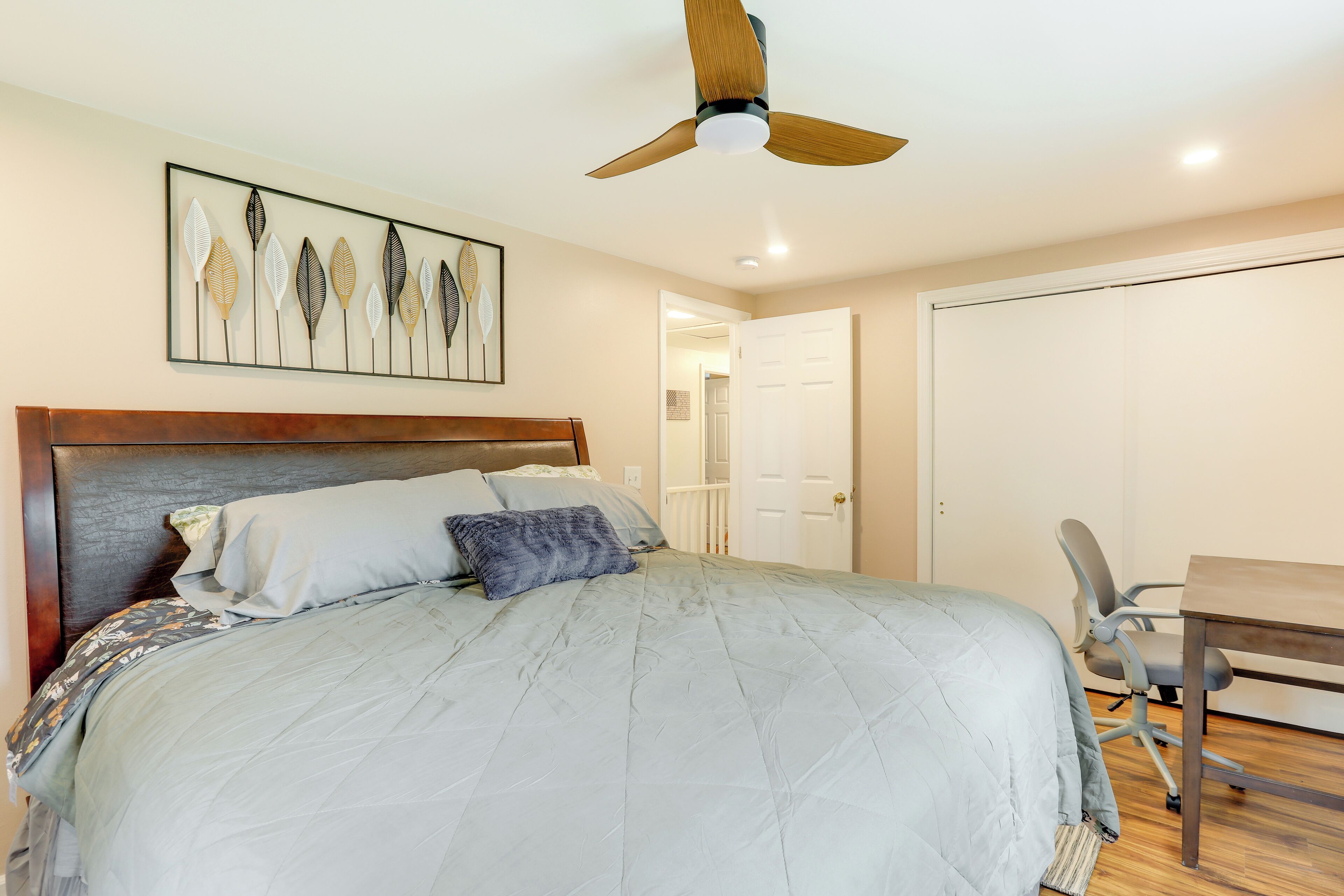 A bedroom with a bed, a desk, and a ceiling fan.