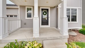 A house with a porch, a front door with a wreath, and a garage. - Pet-friendly Deforest Getaway w/ Backyard! (De Forest)