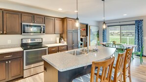 A modern kitchen with granite countertops, stainless steel appliances, and a central island with bar stools. - Pet-friendly Deforest Getaway w/ Backyard! (De Forest)