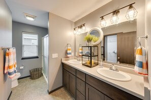 Une salle de bain moderne avec deux lavabos, un grand miroir et un éclairage décoratif.