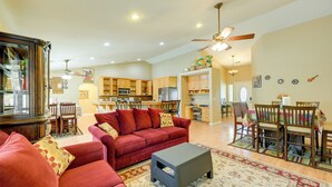 A spacious living room with a red sofa, a coffee table, and a dining area with wooden chairs and a table. - Porterville Getaway w/ Patio + Valley Views! (Porterville)