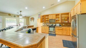 A modern kitchen with wooden cabinets, a stainless steel refrigerator, and a central island with a built-in microwave. - Porterville Getaway w/ Patio + Valley Views! (Porterville)