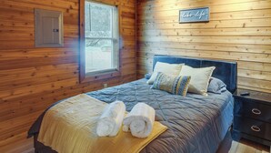 A wooden-paneled bedroom with a bed, pillows, and towels.