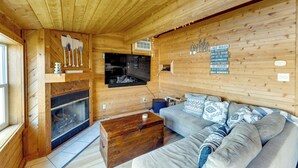 A cozy cabin interior with a fireplace, a sofa, and a wall with various activities listed.