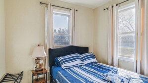 Ein Schlafzimmer mit einem Bett, einem Nachttisch, einer Lampe und einem Sessel.
