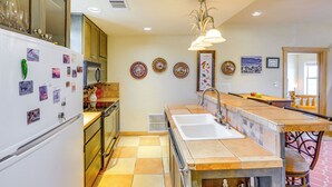 A kitchen with a double sink, a refrigerator, and a dining area with a bench. - Vibrant Terlingua Vacation Rental Near Big Bend! (Terlingua)