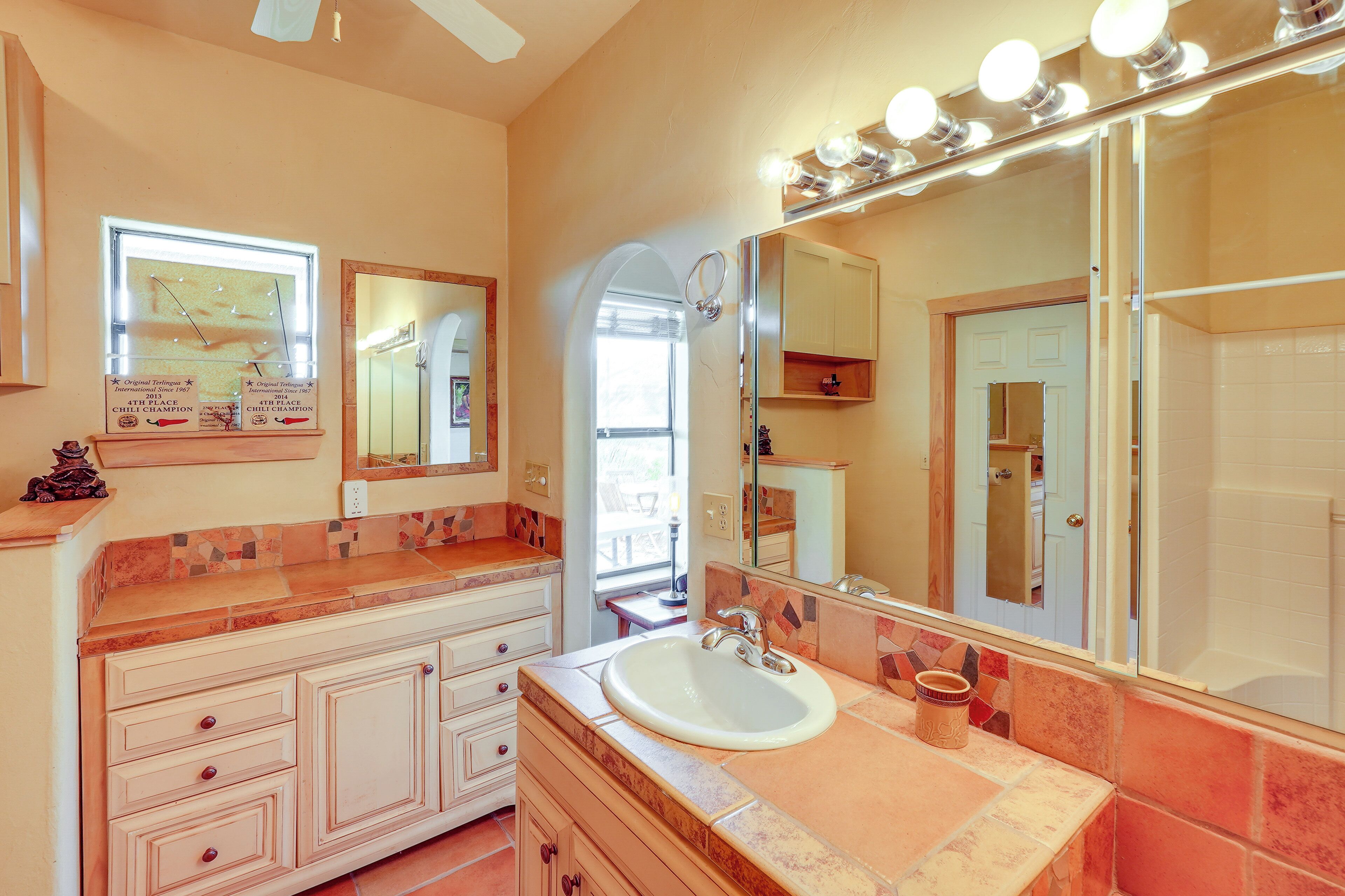A bathroom with a large mirror, vanity, and a sink.