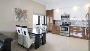 Una cocina moderna con armarios blancos, horno integrado y microondas.