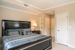 A bedroom with a large bed, a bedside table with a lamp, a wardrobe, and a door. - Spacious Relaxing Modern home steps to beach #1
 (Fort Lauderdale)