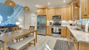 A modern kitchen with wooden cabinets, stainless steel appliances, and a dining area with a bench.