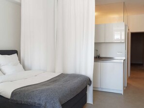 Een slaapkamer met een bed, een nachtkastje en een witte garderobe.