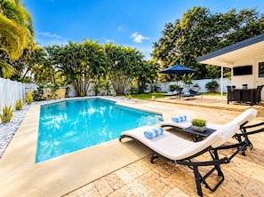 Una piscina con sillones de descanso y un patio.