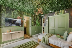 Una habitación con decoración temática en tonos verdes, que incluye una cama, un aparador y un mural en la pared.