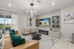 Una sala de estar moderna con un sofá, sillas, una mesa de centro, una chimenea y un televisor grande.