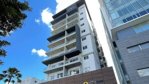 A multi-story building with a modern architectural design, featuring a prominent entrance with a ramp and a sign indicating a hotel. - Downtown*Cozy*1br* POOL* 50MB| Yellowkey (Santo Domingo)