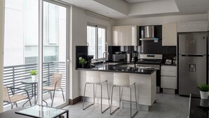 A modern kitchen with a large island, stainless steel appliances, and a balcony with outdoor seating. - Downtown*Cozy*1br* POOL* 50MB| Yellowkey (Santo Domingo)