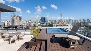 A rooftop terrace with a pool, lounge chairs, and a view of the city skyline. - Downtown*Cozy*1br* POOL* 50MB| Yellowkey (Santo Domingo)