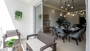 Un comedor con una mesa dispuesta para cuatro personas, rodeada de sillas de mimbre.