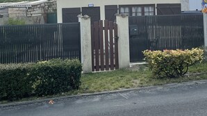 Ein Haus mit Ziegeldach, einem verschlossenen Eingangsbereich und einem kleinen Garten.