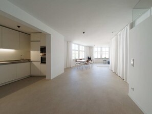 Een ruime, moderne keuken met witte kasten en een eethoek met een tafel en stoelen.