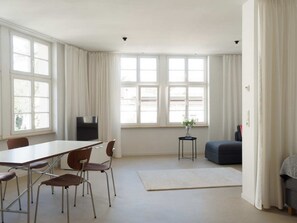 Een ruime kamer met een grote eettafel, stoelen, een bank en een klein bijzettafeltje.