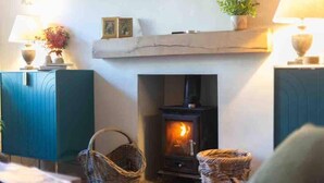 A cozy room with a fireplace, wicker baskets, and a teal cabinet. - Tranquil Appleby House Retreat (Appleby-in-Westmorland)