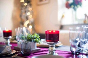 A dining table set with wine glasses, a candle, and a decorative centerpiece.