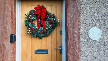 A wooden door with a festive wreath and a metal plate.