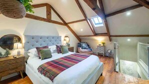 A bedroom with a large bed, wooden beams, a skylight, and a view of the outside. - Tranquil Appleby House Retreat (Appleby-in-Westmorland)