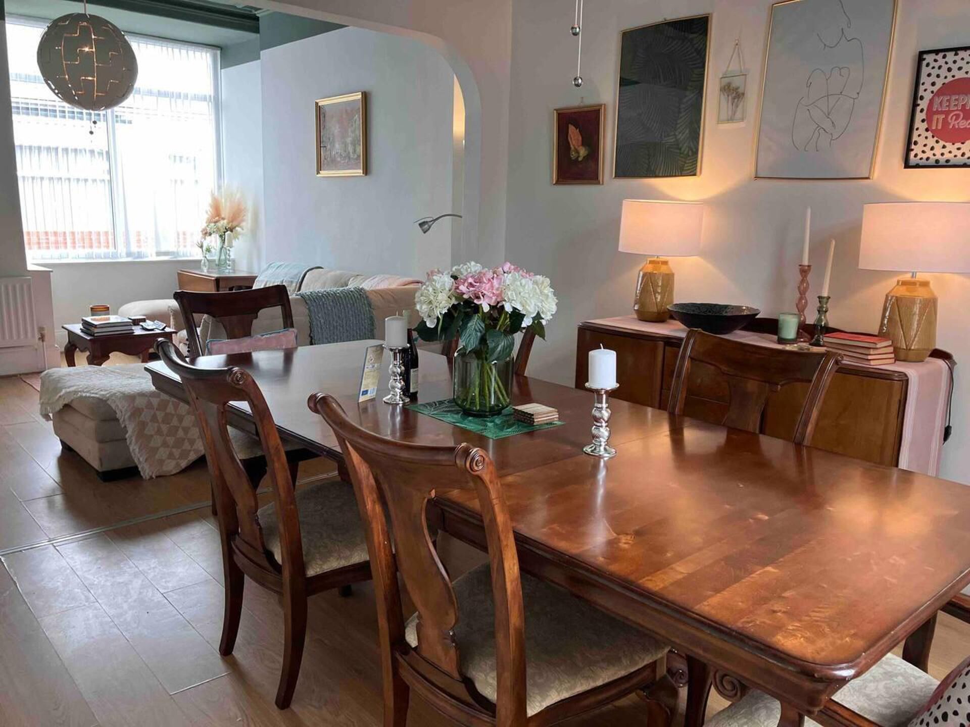 A dining area with a wooden table, chairs, and a vase of flowers.