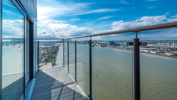 A high-rise building with a balcony overlooking a river and cityscape.