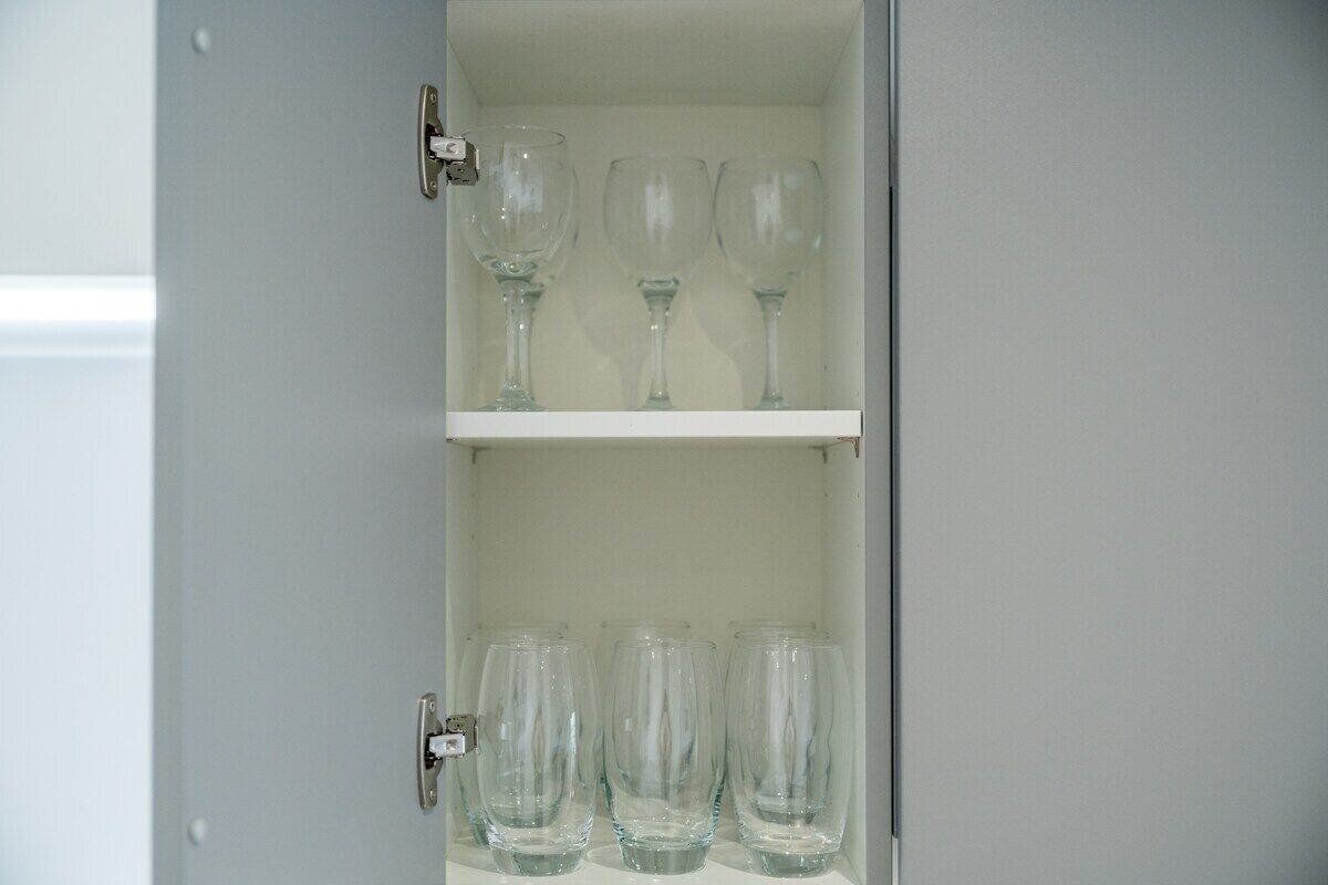 A cabinet with three shelves, each holding clear glassware.