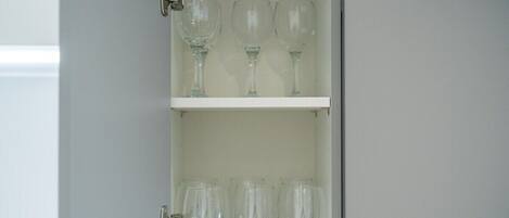 A cabinet with three shelves, each holding clear glassware.