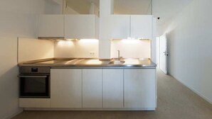 Une cuisine compacte dotée d’appareils électroménagers intégrés, d’un évier et d’un plan de travail.