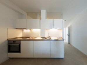 Een kleine keuken met inbouwapparatuur, een spoelbak en een aanrecht.