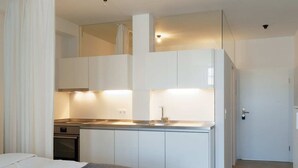 Une chambre d’hôtel de taille réduite, équipée d’une kitchenette, d’un lit et d’une salle de bain.