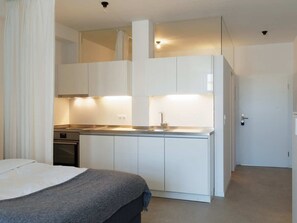 Een compacte hotelkamer met kitchenette, bed en badkamer.