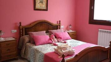 Een slaapkamer met een houten bed, roze wanden en een hanglamp.