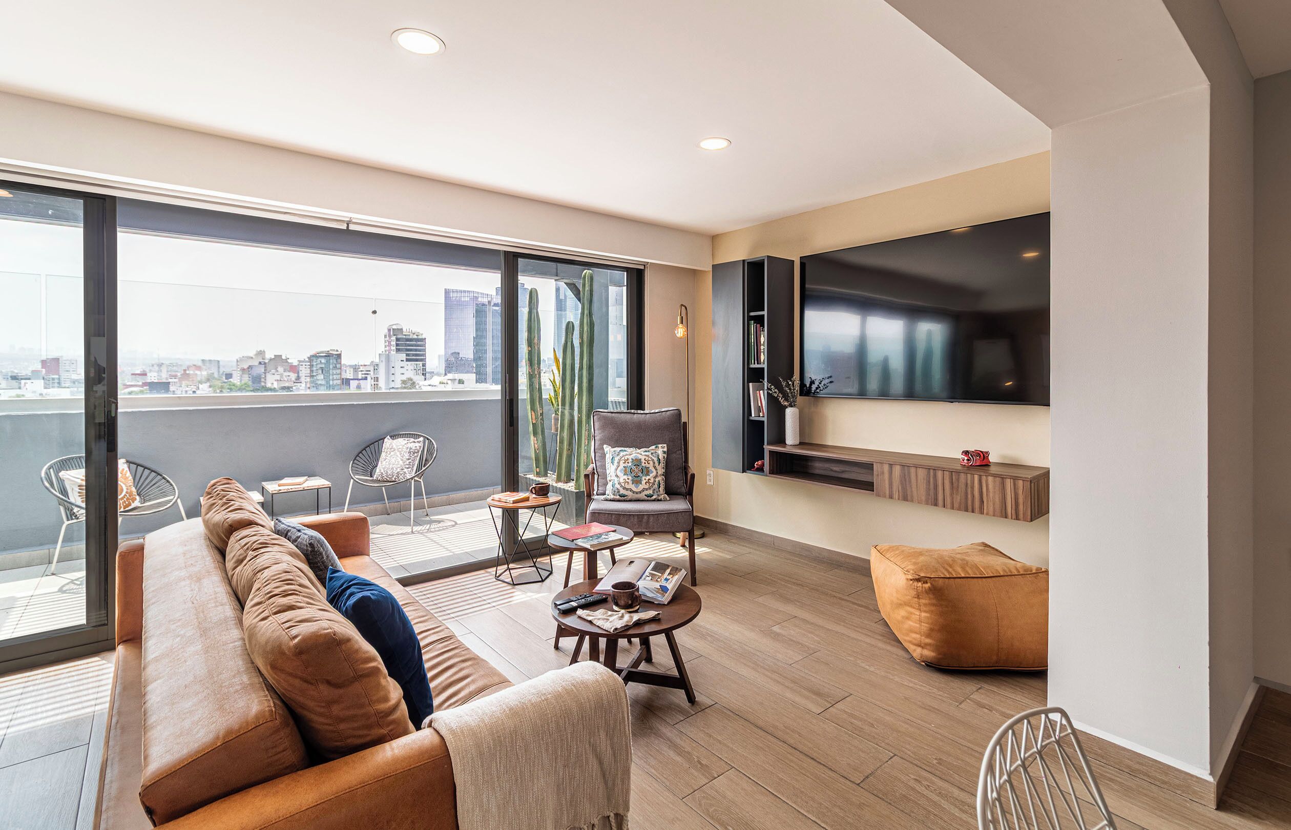 Uma sala de estar moderna com sofá, poltrona, mesa de centro e televisão de tela plana.