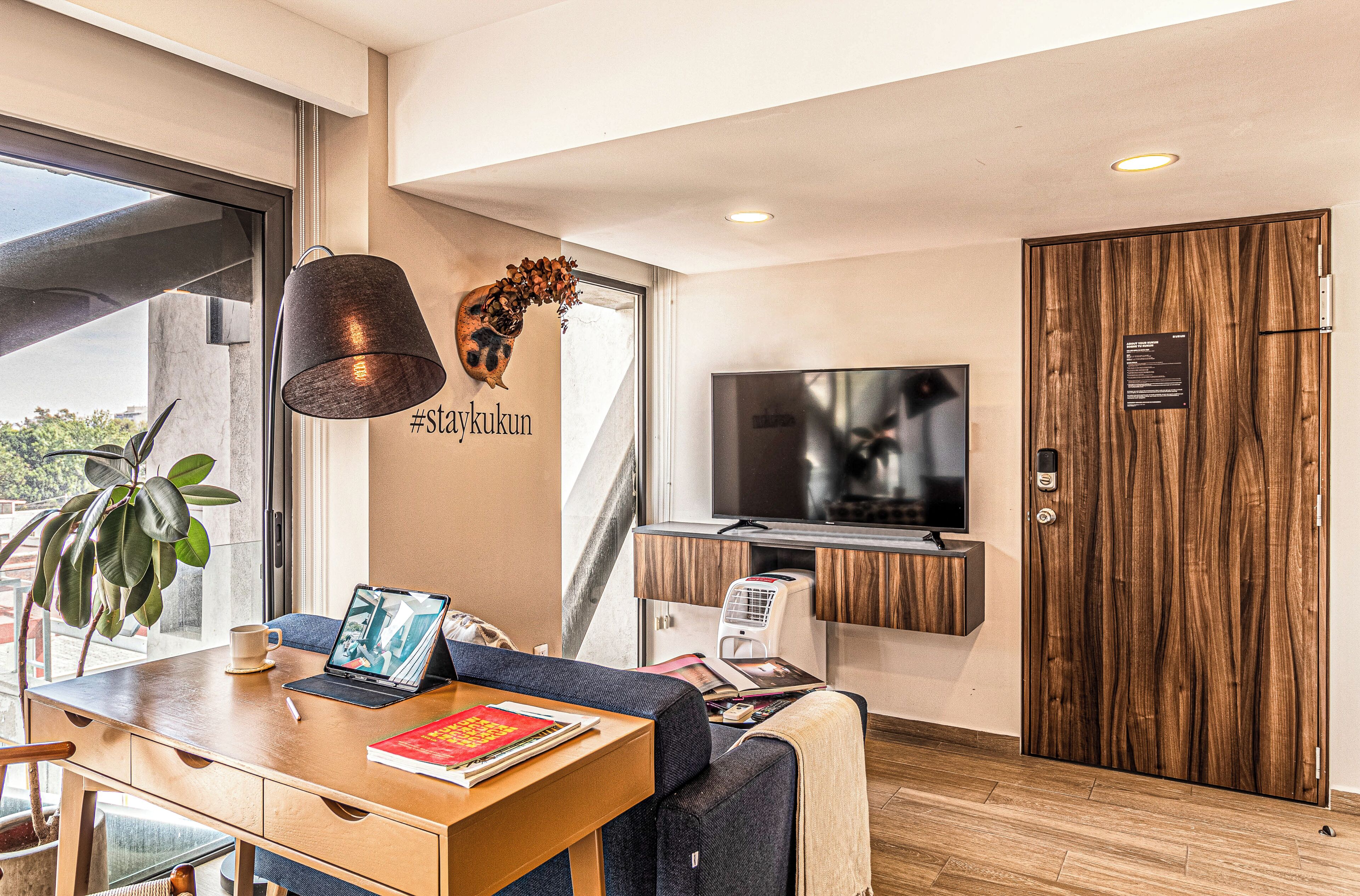 A modern room with a desk, laptop, and a TV mounted on the wall.