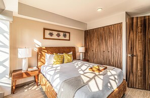 A bedroom with a wooden headboard, a bed with patterned pillows, a bedside table with a lamp, and a wooden wardrobe. - Kukun Tonalá 30 Roma (Mexico City)