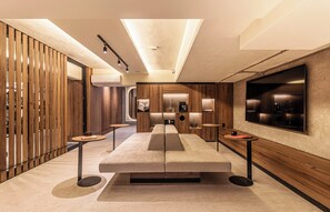 Een modern interieur met een centraal zithoek, houten lambrisering en een grote flatscreen televisie aan de muur.