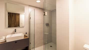 A modern bathroom with a glass-enclosed shower, a white sink, and a mirror above it.