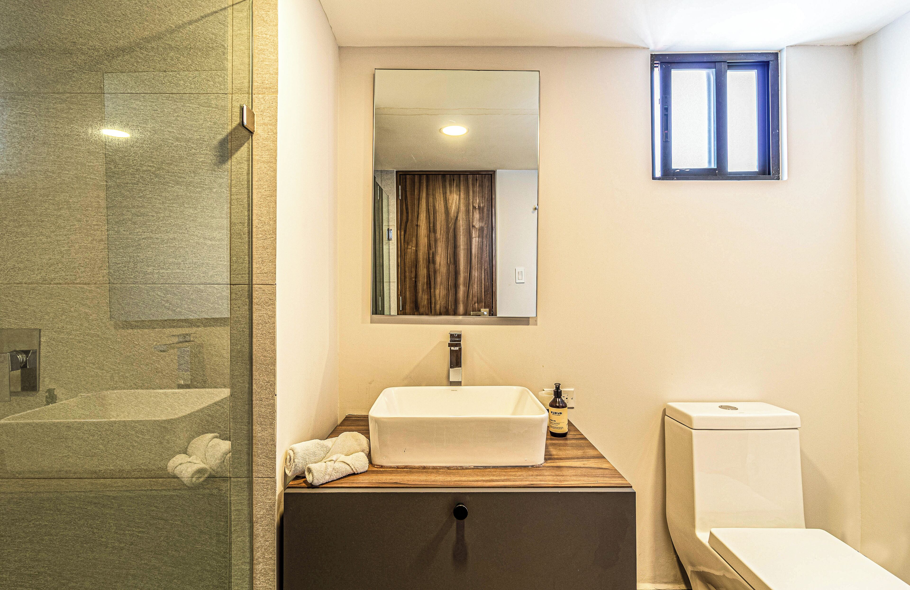 Une salle de bain avec une douche à parois de verre, un meuble-lavabo en bois, un miroir et des toilettes.